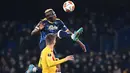 Pemain depan Napoli Victor Osimhen melompat di sebelah bek Barcelona Gerard Piquegur pada play-off fase gugur Liga Europa 2021/2022 di Stadion Diego Armando Maradona, Jumat (25/2/2022) dini hari WIB. Barcelona melaju ke babak 16 besar usai menang telak 4-2 di kandang Napoli. (ANDREAS SOLARO/AFP)
