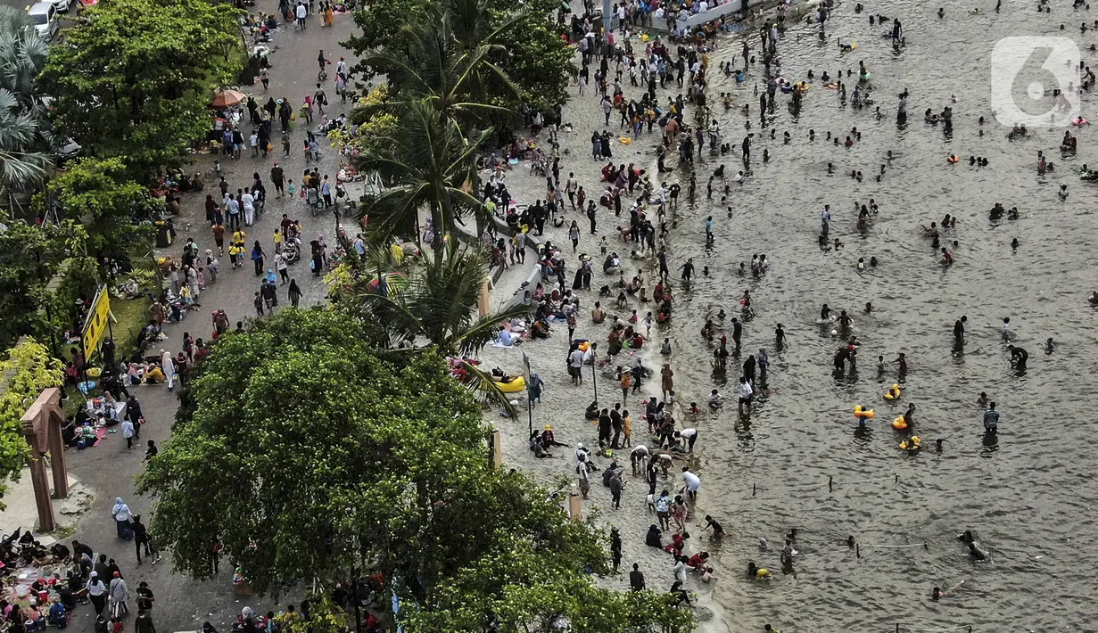Foto udara menunjukkan keramaian pengunjung di Pantai Karnaval Ancol, Jakarta, Jumat (14/5/2021). Pemprov DKI Jakarta pada libur Lebaran 2021 membuka sejumlah tempat wisata, salah satunya Ancol. (Liputan6.com/Johan Tallo)