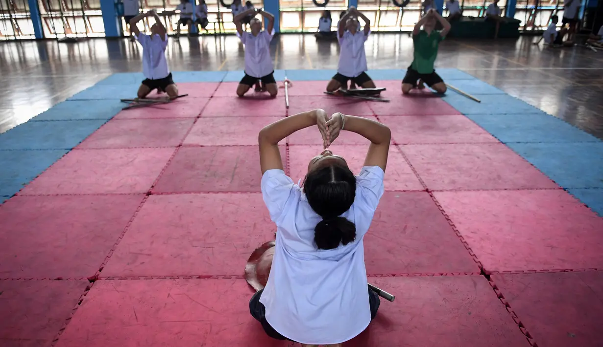 Sejumlah pelajar melakukan pemanasan sebelum berlatih Krabi Krabong di sekolah Thonburee Woratapeepalarak, Thonburi, Bangkok (8/7/2019). Krabi Krabong merupakan seni bela diri Thailand yang dipersenjatai pisau dan perisai kayu yang terabaikan. (AFP Photo/Lillian Suwanrumpha)