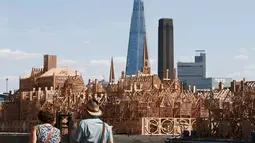 Pejalan kaki melintas di dekat patung skyline Kota London sepanjang 120 meter di London, Inggris, (30/8). Patung ini akan dibakar dalam sebuah acara untuk mengenang bencana Kebakaran besar London pada 1666. (REUTERS/Peter Nicholls)