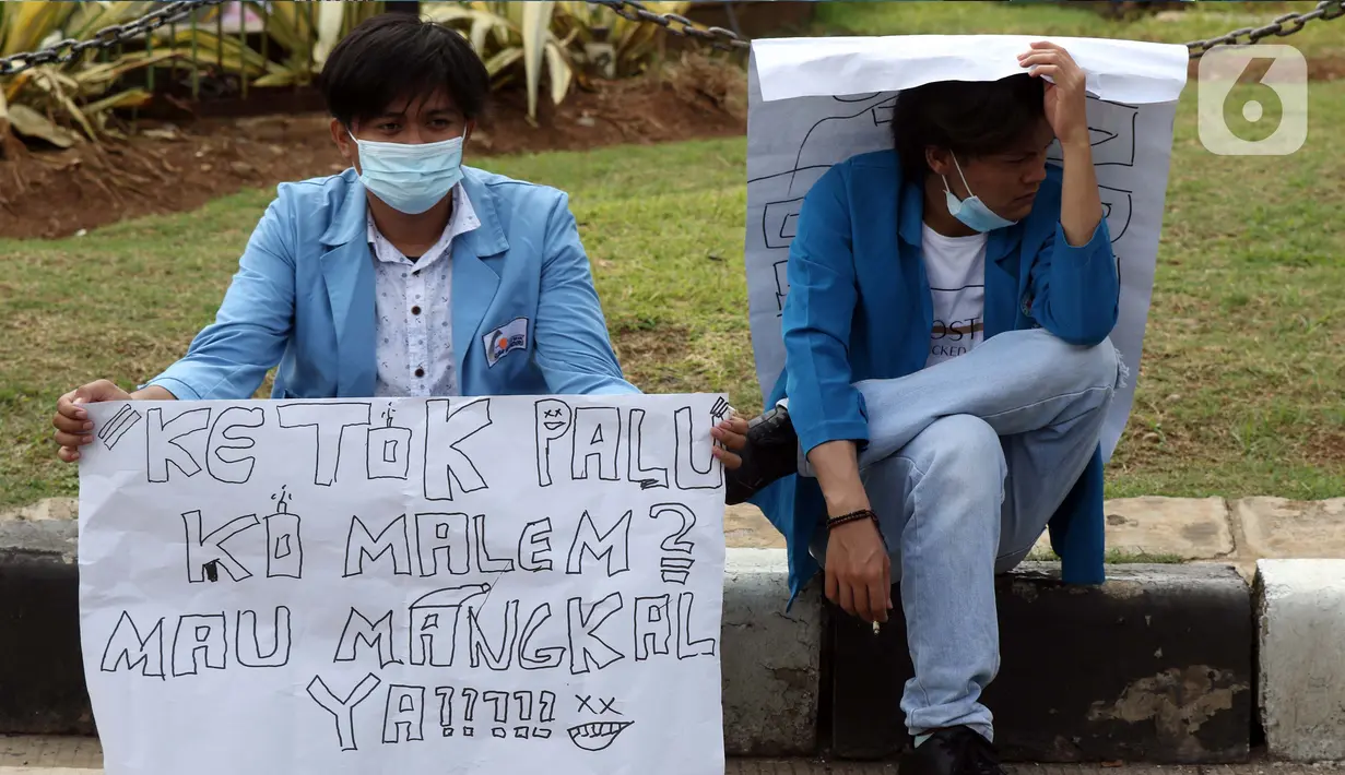 Dua mahasiswa membawa poster saat melakukan aksi unjuk rasa di sekitar kawasan Patung Kuda, Jalan Medan Merdeka Barat, Jakarta, Selasa (20/10/2020). Dalam aksinya, ratusan mahasiswa meminta pemerintah membatalkan pengesahan Omnibus Law UU Cipta Kerja. (Liputan6.com/Helmi Fithriansyah)