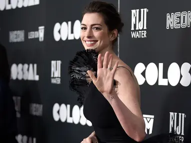 Aktris Anne Hathaway melambaikan tangan ke arah fotografer di karpet merah premiere film 'Colossal', New York City, AS, Selasa (28/3). Aktris pemenang Oscar itu tampil dalam balutan gaun hitam vintage Armani Prive. (Photo by Evan Agostini/Invision/AP)