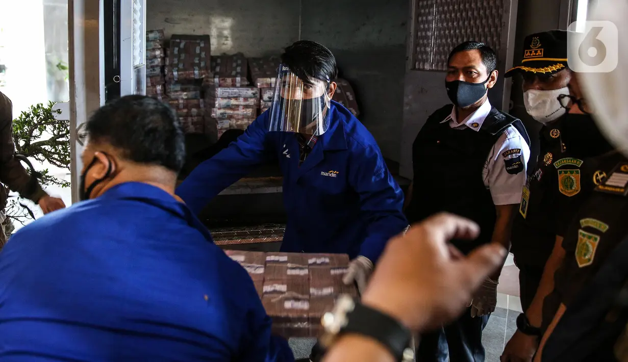 Petugas menurunkan tumpukan uang saat rilis eksekusi barang bukti Honggo Wendratno di Kejaksaan Agung RI, Jakarta, Selasa (7/7/2020). Kejagung menyita barang bukti uang Honggo Wendratno sebesar Rp 97 miliar. (Liputan6.com/Faizal Fanani)