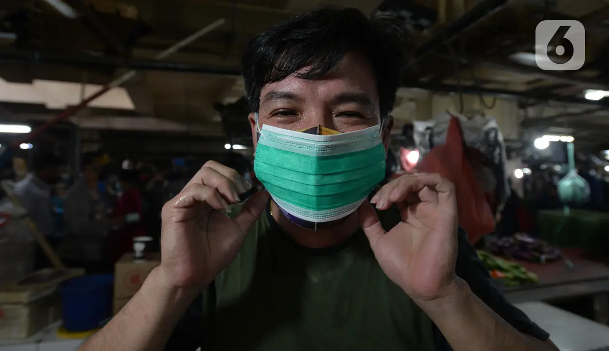 Pedagang mengenakan masker yang dibagikan petugas Polres Jakarta Timur selama sosialisasi di Pasar Palmeriam, Matraman, Selasa (9/2/2021). Kegiatan tersebut sebagai upaya meningkatkan kesadaran akan pentingnya penerapan protokol kesehatan untuk menekan penyebaran Covid-19. (merdeka.com/Imam Buhori)