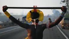 Masyarakat suku Kayapo memegang tongkat saat memblokir jalan raya utama Trans-Amazonian di Negara Bagian Para, Brasil (17/8/2020). Aksi tersebut dilakukan di tengah pandemi Covid-19 ini sebagai unjuk rasa adat. (AFP Photo/Carl De  Souza)