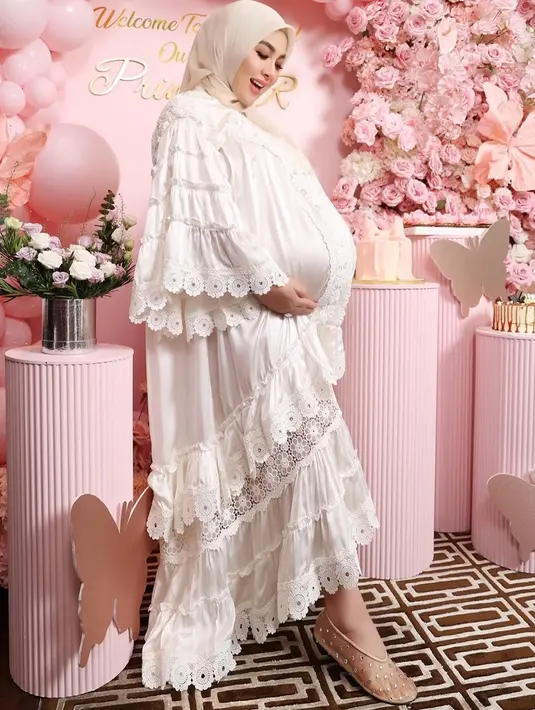 Untuk look kedua, Syahrini memilih gaun renda berwarna pink muda cerah. Penampilannya juga dilengkapi dengan hijab segi empat berwarna nude pink yang sama seperti sebelumnya.  [@princessyahrini].