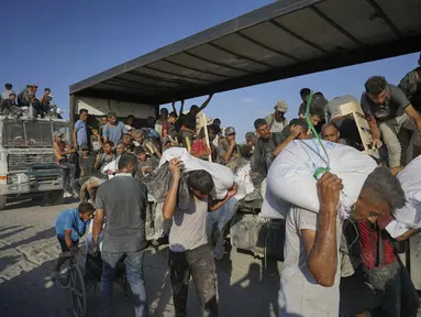 Warga Palestina membawa karung-karung tepung yang diturunkan dari konvoi bantuan kemanusiaan dalam perjalanan menuju Kota Gaza dari Jalur Gaza utara, Kamis 31 Juli 2025. (AP Photo/Jehad Alshrafi)
