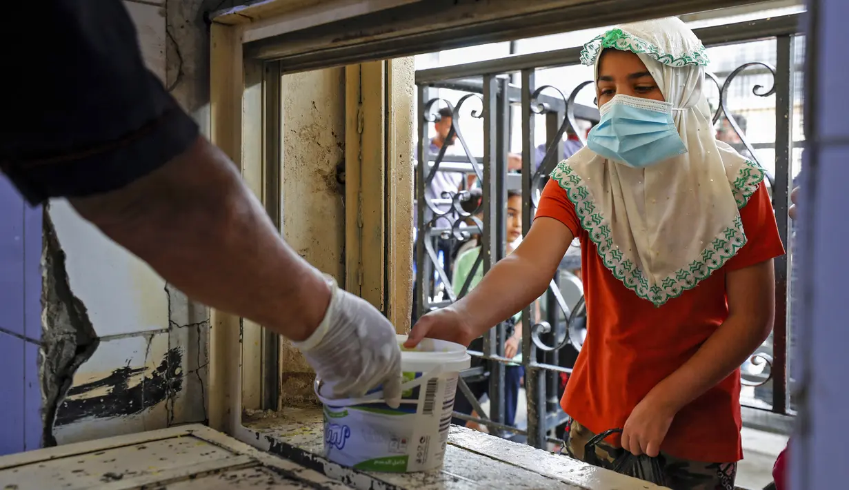 Seorang anak yang membutuhkan menerima makanan berbuka puasa dari juru masak di dapur Masjid Muslim Sunni Abdel Kader al-Kilani, Baghdad, Irak, 19 April 2021. Kegiatan ini berlangsung selama bulan suci Ramadhan. (AHMAD AL-RUBAYE/AFP)