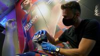 Penjaga toko memasang masker berlogo Barcelona ke Manekin di Toko Asesoris Barcelona, Senin (25/5/2020). Di tengah pandemi virus Corona, Barcelona menjual masker dengan harga 18 euro atau sekitar Rp 291 ribu. (AFP/Lluis Gene)
