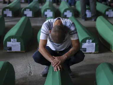 Seorang pria muslim berduka di samping peti mati kerabatnya, korban genosida Srebrenica 1995, di Potocari, Bosnia, Minggu (9/7/2023). Sebanyak 30 jenazah korban pembantaian Srebrenica yang baru diidentifikasi, satu-satunya genosida yang diakui di Eropa sejak Perang Dunia II, tiba di Pusat Peringatan di Potocari dimana mereka akan dimakamkan pada 11 Juli. (AP Photo/Armin Durgut)