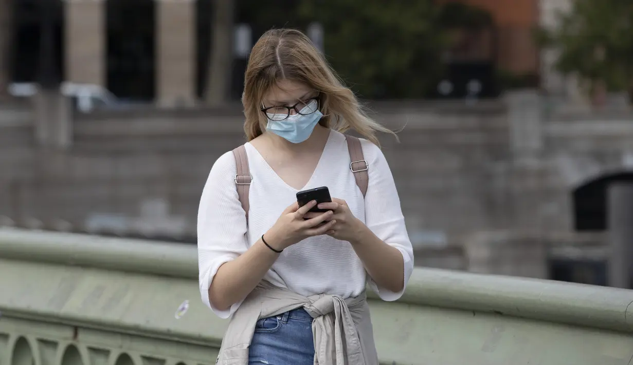 Seorang wanita yang mengenakan masker berjalan di Jembatan Westminster di London, Inggris (8/9/2020). Warga Inggris didesak untuk menangani pandemi dengan serius atau menghadapi "jalan bergelombang" di masa yang akan datang. (Xinhua/Han Yan)