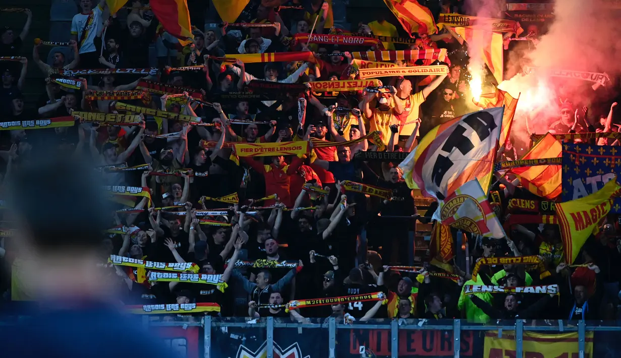 Suporter FC Metz menyalakan suar saat mendukung timnya pada laga lanjutan Liga Prancis 2023/2024 melawan RC Lens di Saint-Symphorien Stadium, Longeville-les-Metz, Prancis, Sabtu (13/04/2024) dini hari WIB. (AFP/Jean-Christophe Verhaegen)