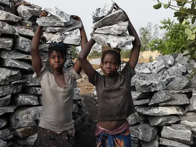  Bocah perempuan mengangkat bongkahan batu saat bekerja di sebuah tambang di Ouagadougou, Burkina Faso, 21 Desember 2015. 12 Juni ditetapkan sebagai Hari Penentangan Pekerja Anak Sedunia. (NABILA EL Hadad / AFP)