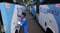 Petugas membersihkan Kopaja terintegrasi Transjakarta terparkir di Parkir Timur Senayan, Jakarta, Selasa (22/12). Saat ini terdapat 320 bus tampilan baru Kopaja AC yang akan beroperasi di rute-rute yang terintegrasi.  (Liputan6.com/Johan Tallo)