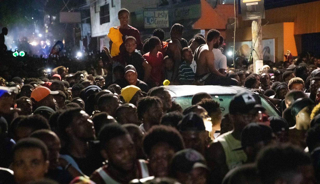 Bersama Curacao dan Panama, Haiti menjadi tiga tim terbaru dari zona CONCACAF yang memastikan tempat di Piala Dunia 2026. Tampak dalam foto, warga Haiti turun ke jalan-jalan di Port-au-Prince saat merayakan lolosnya tim nasional mereka di putaran final Piala Dunia 2026, pada Selasa 18 November 2025 waktu setempat. (Clarens SIFFROY/AFP)
