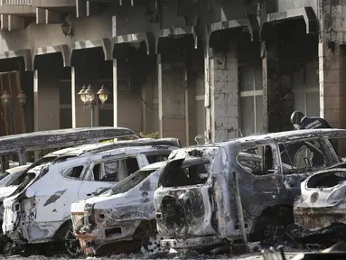 Petugas kepolisian memeriksa mobil yang hangus terbakar pasca teror di luar hotel Splendid, Ouagadougou , Burkina Faso, (16/1). Petugas berhasil merebut kembali lokasi dimana beberpa kelompok al Qaeda menyandera beberapa orang. (REUTERS / Joe Penney)