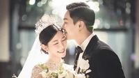 Mengenakan gaun pengantin yang elegan dan tiara mewah, Lee Da In memegang karangan bunga dan tersenyum cerah, sementara suaminya Lee Seung Gi, mengenakan tuksedo di sampingnya, berpose dengan tangan di sakunya dan mencium keningnya. [Foto: IG/byhumanmade]