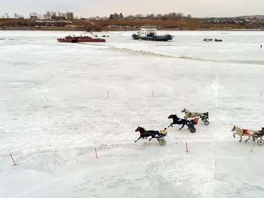 Peserta memacu troika selama bersaing dalam balapan kuda Ice Derby di Sungai Yenisei yang membeku, Krasnoyarsk, Rusia (16/3). Ice Derby merupakan kejuaraan balap kuda amatir yang berlangsung setiap akhir musim dingin. (Reuters/Ilya Naymushin)