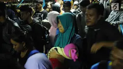 Pemudik menggendong balita ikut dalam antrian masuk ke dalam kapal penyeberangan di Dermaga I Pelabuhan Merak, Banten, Kamis (22/6). Dini hari, ribuan pemudik menyeberang dari Pelabuhan Merak menuju Bakauheni, Lampung. (Liputan6.com/Helmi Fithriansyah)