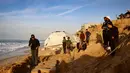 Memasuki detik-detik pergantian tahun, krisis kemanusiaan di Jalur Gaza masih sangat memprihatinkan. Tampak dalam foto, warga menyaksikan seniman Yazed Abo Jarad membuat patung pasir untuk tahun mendatang di Deir El-Balah, Jalur Gaza tengah pada 30 Desember 2025. (Bashar Taleb/AFP)