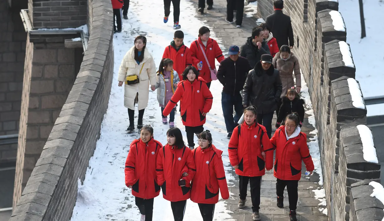 Wisatawan berjalan  menikmati suasana salju di lingkungan Tembok Besar China di utara Beijing (6/1/2020). Salju yang turun tidak menyurutkan para wisatawan baik lokal maupun dari mancanegara untuk berkunjung ke Tembok Besar China. (AFP/Greg Baker)