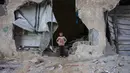 Seorang anak laki-laki berdiri di celah tembok rumahnya yang hancur akibat serangan Israel di Khan Younis, Jalur Gaza selatan, pada Rabu 29 Oktober 2025. Serangan Israel terjadi beberapa jam setelah Presiden Amerika Serikat (AS) Donald Trump mengatakan "tidak ada" yang akan membahayakan perjanjian gencatan senjata yang ia bantu mediasi. (BASHAR TALEB/AFP)