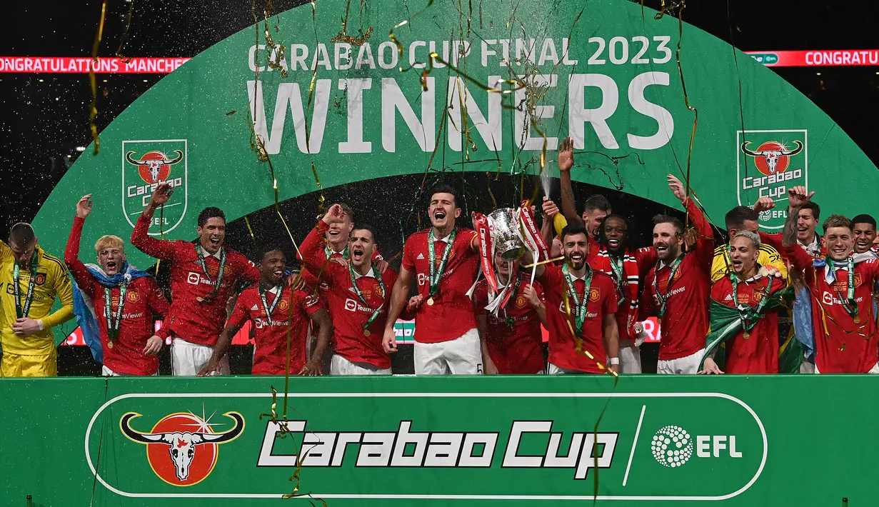 Pemain Manchester United merayakan kemenangan dengan mengangkat trofi Carabao Cup 2023 setelah mengalahkan Newcastle United di Wembley Stadium, Minggu (26/2/2023) waktu setempat. Kemenangan ini sekaligus mengakhiri enam tahun puasa gelar. (AFP/Glyn Kirk)