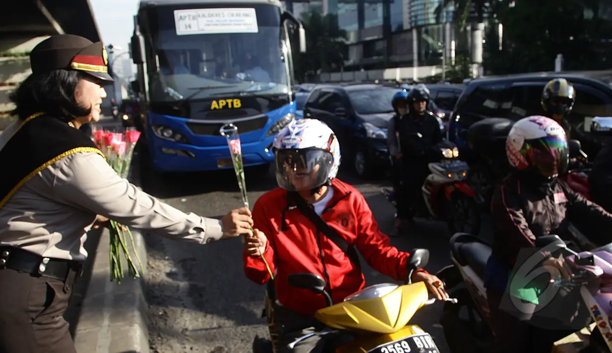 Para pengendara motor di kawasan Slipi mendapat bunga dari seorang Polwan, Jakarta, Selasa (21/4/2015). Pembagian bunga ini dalam rangka memperingati hari Kartini.(Liputan6.com/Johan Tallo)