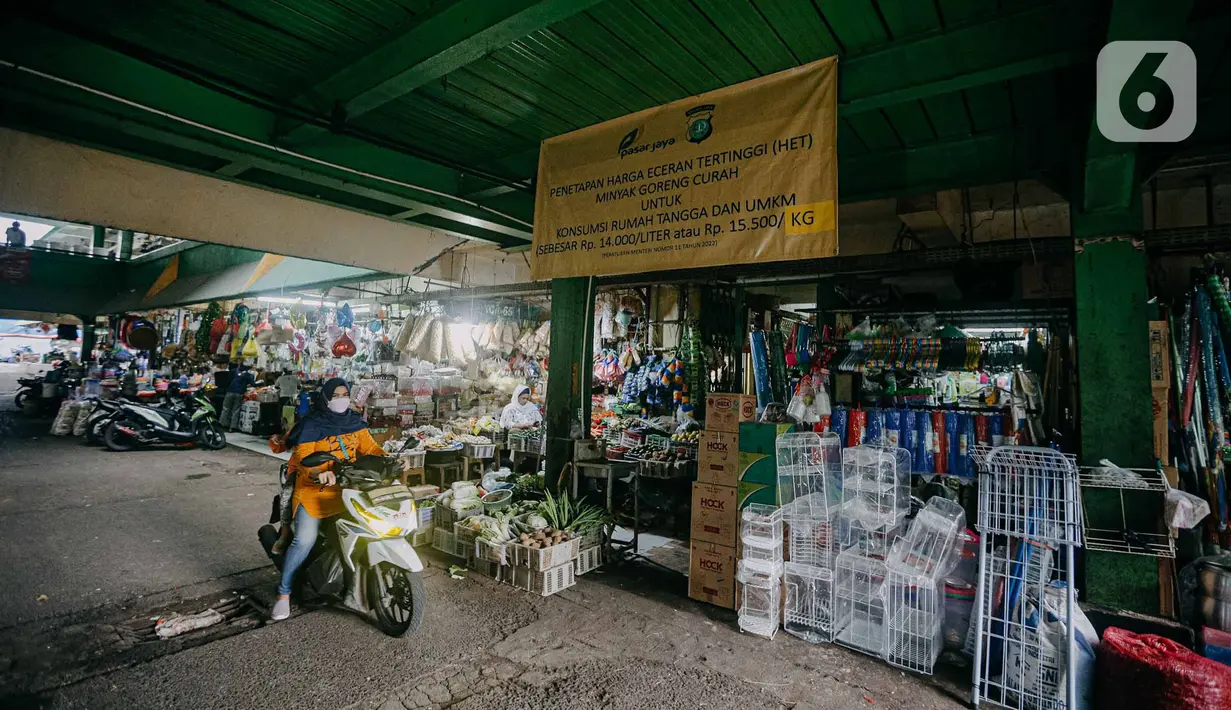 Pengendara motor melintas di dekat spanduk terkait penetapan harga minyak goreng subsidi di lorong Pasar Kramat Jati, Jakarta, Senin (30/5/2022). Adanya spanduk minyak goreng subsidi tersebut  untuk mensosialisasikan soalnya Per 31 Mei 2022 pemerintah berencana mencabut subsidi minyak goreng curah. (Liputan6.com/Faizal Fanani)