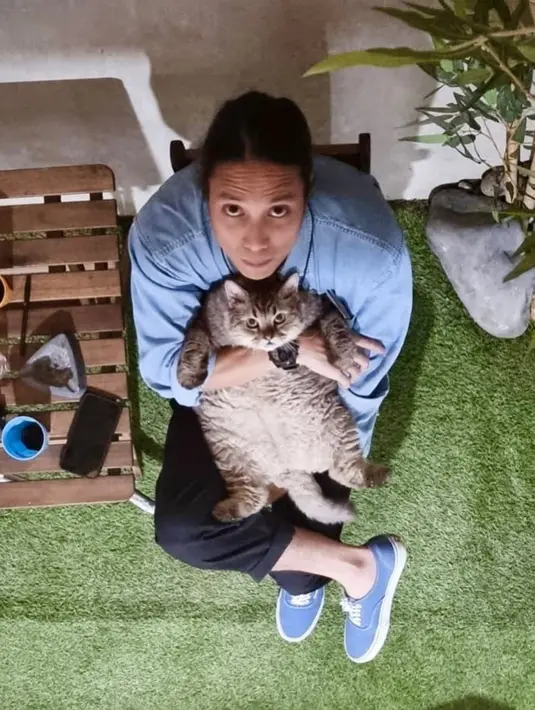 Potret gemas Dikta dan Jimbon saat menatap ke arah kamera yang ada di atas kepala keduanya. Penyanyi yang pernah yang menjadi atlet tenis ini memelihara Jimbon sejak umur kucingnya baru tiga bulan hingga sekarang berusia 9 tahun. (Instagram/@dikta)