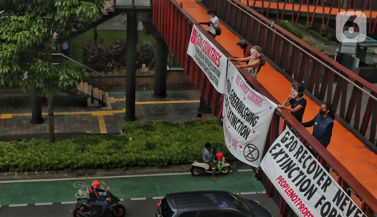 Sejumlah aktivis yang tergabung dalam Extintion Rebellion (XR) dan Walhi Jakarta melakukan aksi di JPO Pinisi, Jalan Jenderal Sudirman, Jakarta, Senin (14/11/2022). Aksi tersebut dilakukan untuk menyerukan kepada para pemimpin agar menghentikan “pencucian hijau” dan praktik ekonomi “business-as-usual” yang secara sistematis memperburuk krisis iklim dan mendorong umat manusia pada kehancuran ekologis & kepunahan massal. Negara-negara G20 turut menyumbang atas 80 persen emisi karbon dunia dan 60 persen populasi penduduk bumi. (Liputan6.com/Angga Yuniar)