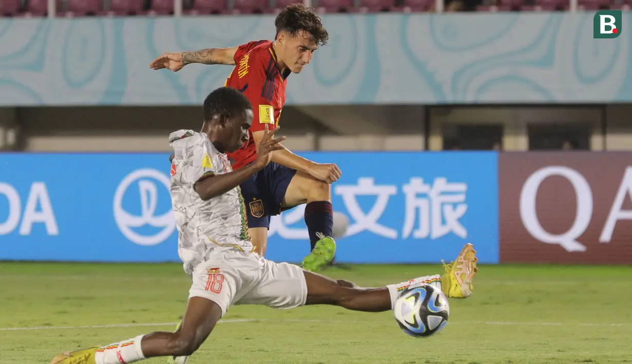 <p>Pemain Timnas Spanyol U-17, Roberto Martin (kanan) berusaha dihadang oleh pemain Mali U-17, Moussa Massire Diop dalam pertandingan babak penyisihan Grup B Piala Dunia U-17 di Stadion Manahan, Solo. Senin (13/11/2023). (Bola.com/Arief Bagus)</p>