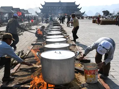 Para pria menyiapkan "Banh Chung" atau kue beras tradisional Vietnam untuk amal, menjelang Tahun Baru Imlek atau festival Tet di Pagoda Tam Chuc di provinsi Ha Nam (7/1/2023). Banh Chung adalah kelezatan khas Vietnam yang terbuat dari ketan, daging babi, dan kacang hijau yang dibungkus dengan daun pisang dan dimasak selama 10 jam. (AFP/Nhac Nguyen)