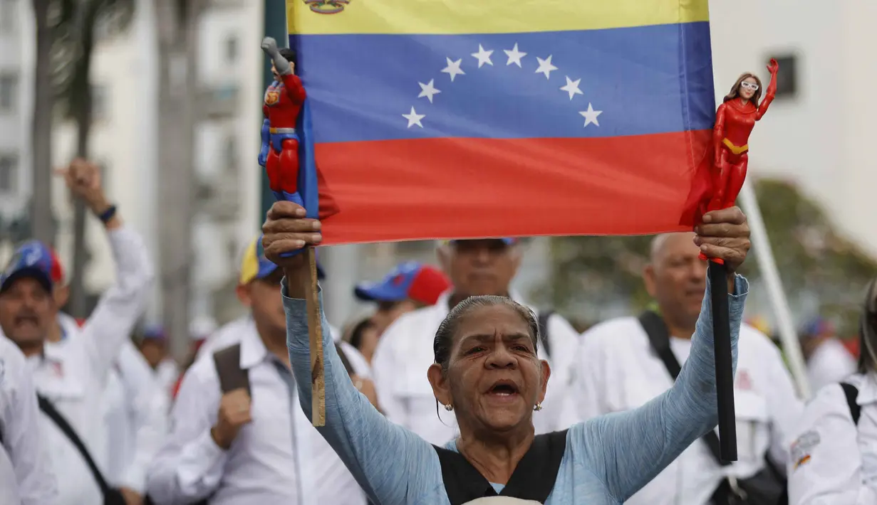 Para pengunjuk rasa mengecam tindakan Amerika Serikat yang dianggap melanggar kedaulatan Venezuela. Tampak dalam foto, seorang wanita memegang bendera nasional Venezuela selama pawai dukungan untuk mantan Presiden Venezuela Nicolas Maduro yang diselenggarakan oleh para pekerja di Caracas pada 14 Januari 2026. (Pedro MATTEY/AFP)