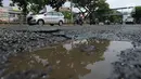 Sejumlah kendaraan melewati jalan berlubang yang masih tergenang air di ruas Jalan Lapangan Ros, Tebet, Jakarta, Sabtu (11/5/2019). Jalan-jalan berlubang yang terisi air tersebut dapat mengakibatkan kecelakaan bagi pengendara kendaraan bermotor. (merdeka.com/Imam Buhori)