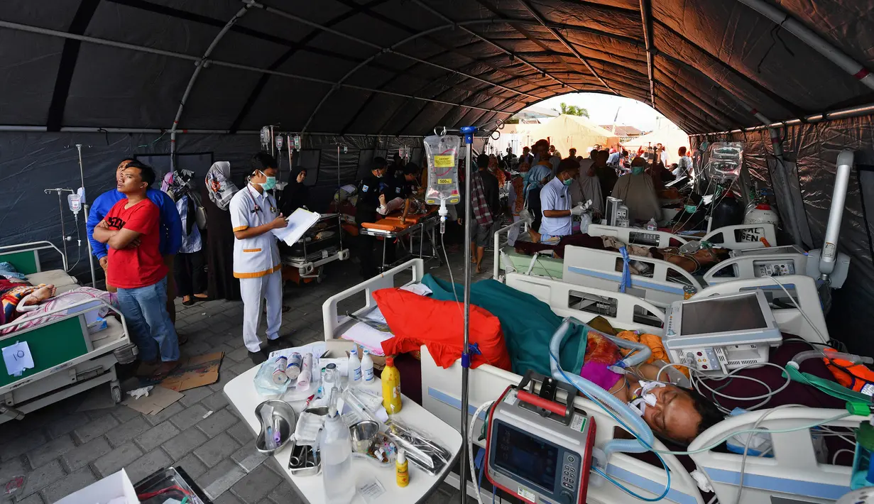 Korban gempa menjalani perawatan di bangsal darurat luar Rumah sakit Moh. Ruslan di Mataram, Senin (6/8). Aparat gabungan terus melakukan evakuasi dan penanganan darurat akibat bencana gempa bermagnitudo 7 yang mengguncang Lombok. (AFP/ADEK BERRY)