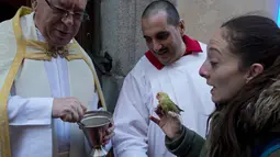Pastor memberkati seekor burung peliharaan pada peringatan Hari santo Antonius di gereja Saint Pablo, Spanyol, Rabu (17/1). Pemberkatan hewan peliharaan ini sudah ada sejak abad ke-19 di Madrid, Kepulauan Balearic dan Burgos. (AP/Alvaro Barrientos)