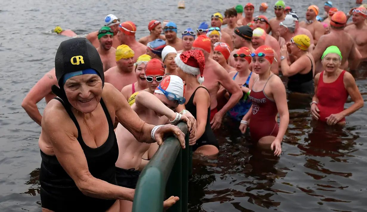Sejumlah perenang naik meninggalkan danau usai mengikuti lomba berenang di Danau Serpentine di Hyde Park, London, Inggris, Minggu (25/12). Lomba ini digelar untuk merayakan Natal 2016. (REUTERS/Toby Melville)