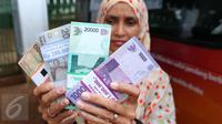 Warga menunjukkan uang kertas usai ditukarkan di penukaran uang keliling di Lapangan IRTI Monas, Jakarta, Senin (13/6). BI dan 20 bank umum lainnya membuka pelayanan penukaran uang di Monas yang dimulai 10 Juni 2016 kemarin. (Liputan6.com/Angga Yuniar)