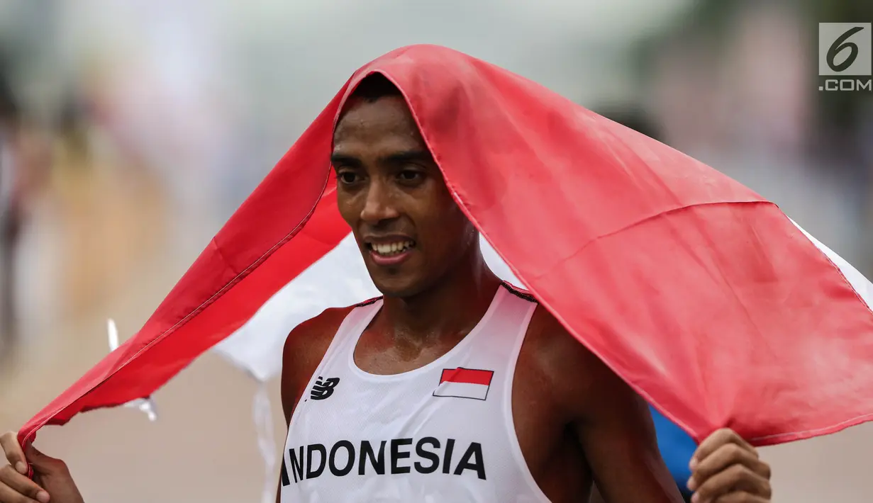 Pelari Indonesia Agus Prayogo membawa Bendera Merah Putih usai melakukan trek maraton SEA Games XXIX di di Putrajaya, Kuala Lumpur, Malaysia, Sabtu (19/8). Rui Yong meraih emas dengan catatan waktu dua jam 29 menit 27 detik. (Liputan6.com/Faizal Fanani)