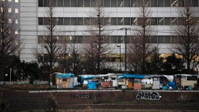 Kamp tunawisma berjajar dekat bangunan komersial di sepanjang Sungai Kama, Kawasaki, Jepang, Selasa (14/1/2020). Jepang dinilai kurang murah hati dengan kesejahteraan sosial daripada negara-negara di Eropa, dan tidak memiliki jenis badan amal swasta yang lazim di AS (AP Photo/Jae C. Hong)
