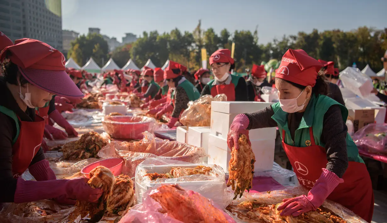 Peserta membuat kimchi, hidangan tradisional Korea Selatan, selama Festival Kimchi tahunan di Seoul (2/11). Hidangan tradisional berupa kubis yang difermentasi dan lobak ini hasilnya akan didonasikan untuk kaum minoritas di Korsel.  (AFP Photo/Ed Jones)