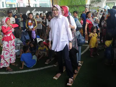 Wali Kota Tangerang Selatan Airin Rachmi Diany mencoba permainan bakiak di Taman Bermain Masyarakat (TBM) Kolong Ciputat, Tangsel, Banten, Minggu (22/7). Kegaiatan ini untuk merayakan Hari Anak Nasional. (Merdeka.com/Arie Basuki)