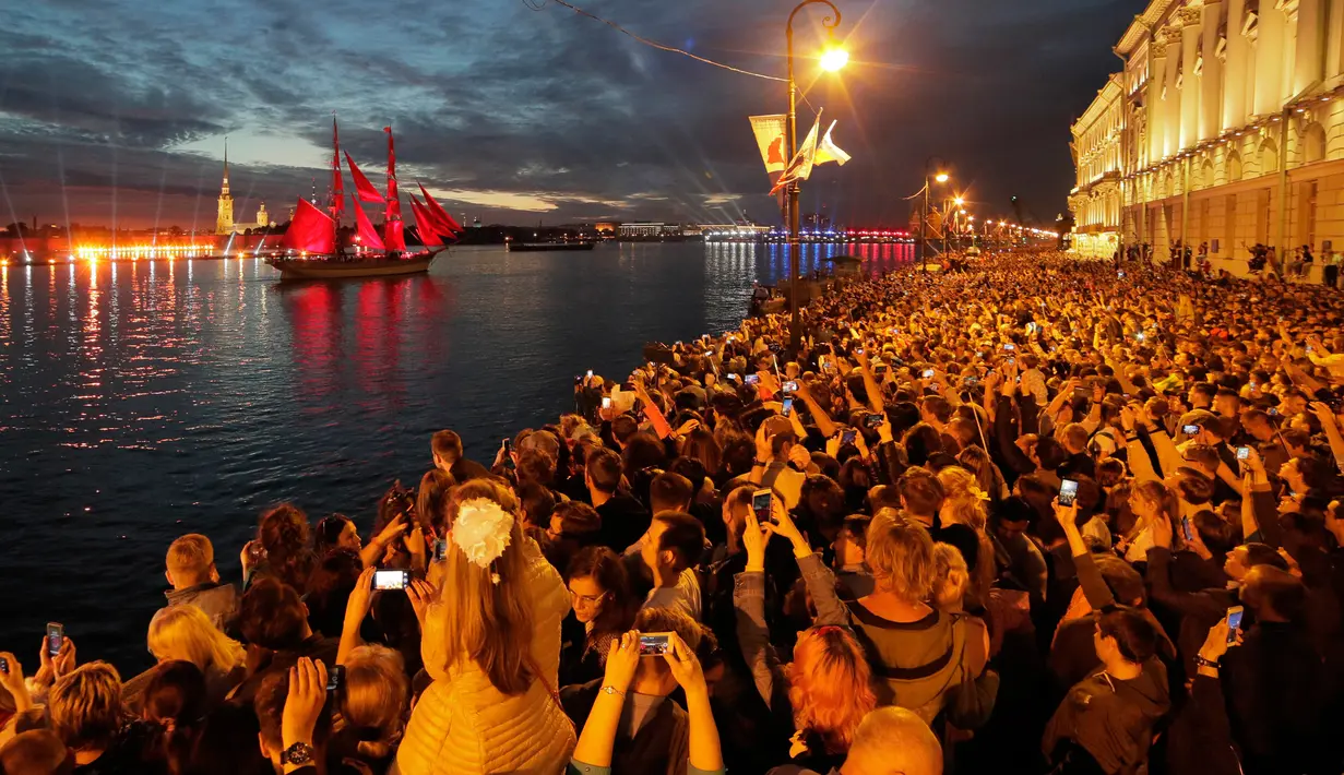 Orang-orang menonton kembang api dan perahu berlayar merah saat White Nights Festival di St.Petersburg, Rusia (24/6). Atraksi terbesar untuk memperingati White Nights adalah Alye Parusa atau Scarlet Sails (Layar Merah). (AP/Dmitri Lovetsky)