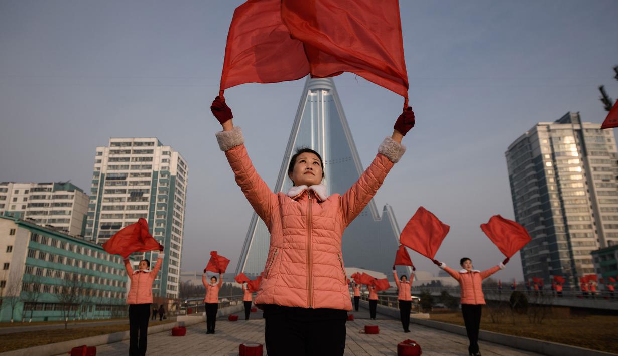 Kelompok Serikat Wanita Sosialis mengibarkan bendera saat melakukan propaganda di depan Hotel Ryugyong, Pyongyang, Korea Utara, Sabtu (9/3). Mereka melakukan aksinya di lokasi-lokasi strategis sekitar Pyongyang pada hari Senin-Sabtu. (Ed Jones/AFP)
