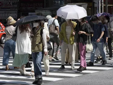 Orang-orang berjalan di atas penyeberangan pejalan kaki di bawah terik matahari di Tokyo, Senin (30/5/2022). Cuaca panas pada hari Senin telah ditetapkan dengan suhu naik lebih dari 27 derajat Celcius (80,6 derajat Fahrenheit) di Tokyo, menurut Badan Meteorologi Jepang. (AP Photo/Eugene Hoshiko)