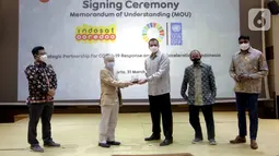 Resident Representative UNDP Indonesia, Norimasa Shimomura (kedua kiri) dan Presdir & CEO Indosat Ooredoo, Ahmad Al-Neama (tengah) bertukar cindermata usai menandatangani MoU penanggulangan pandemi COVID-19 dan percepatan pencapaian SDGs, di Jakarta, Rabu (31/3/2021). (Liputan6.com/Pool/Indosat)