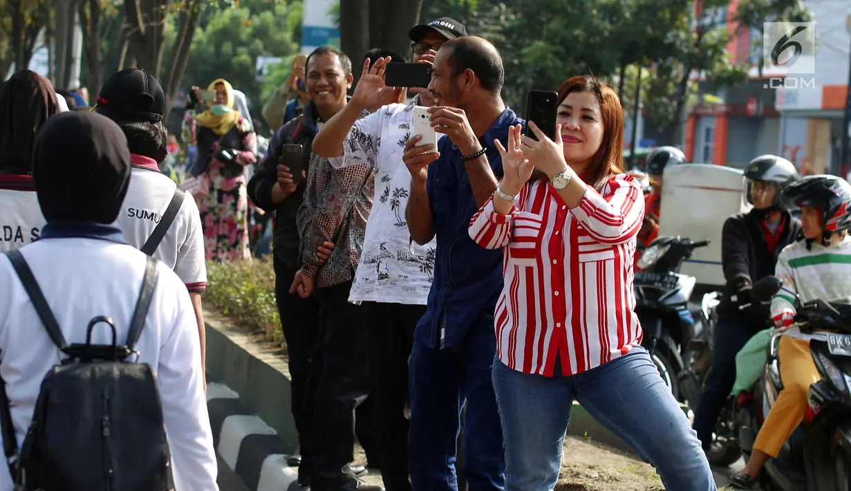 Warga mengabadikan momen simulasi kirab pernikahan Kahiyang Ayu dan Bobby Nasution, Medan, Rabu (22/11). Simulasi kirab ngunduh mantu Jokowi menjadi pusat perhatian warga sekitar. (Liputan6.com/Johan Tallo)