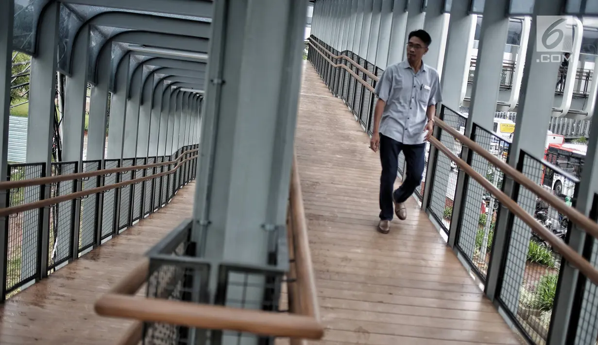 Pejalan kaki melintas di jembatan penyeberangan orang (JPO) Bundaran Senayan, Jakarta, Senin (21/1). JPO Bundaran Senayan mengedepankan konsep minimalis modern. (Liputan6.com/Faizal Fanani)