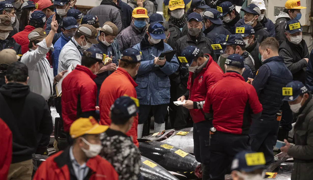 Penjual dan pembeli grosir menghadiri lelang tuna pertama Tahun Baru di pasar ikan Toyosu di Tokyo (5/1/2023). Pada tahun ini, lelang tuna tertinggi terjual lebih dari USD 270.000. Hampir dua kali lipat dari harga tahun lalu. (AFP/Richard A. Brooks)